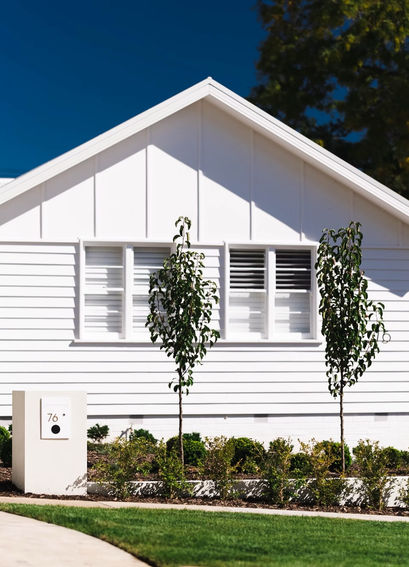 White weatherboard entry with brick planter steps and layered planting