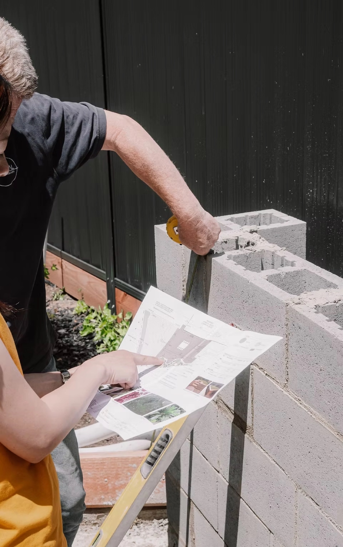 Capital DCM builder setting a masonry block retaining wall against construction drawings