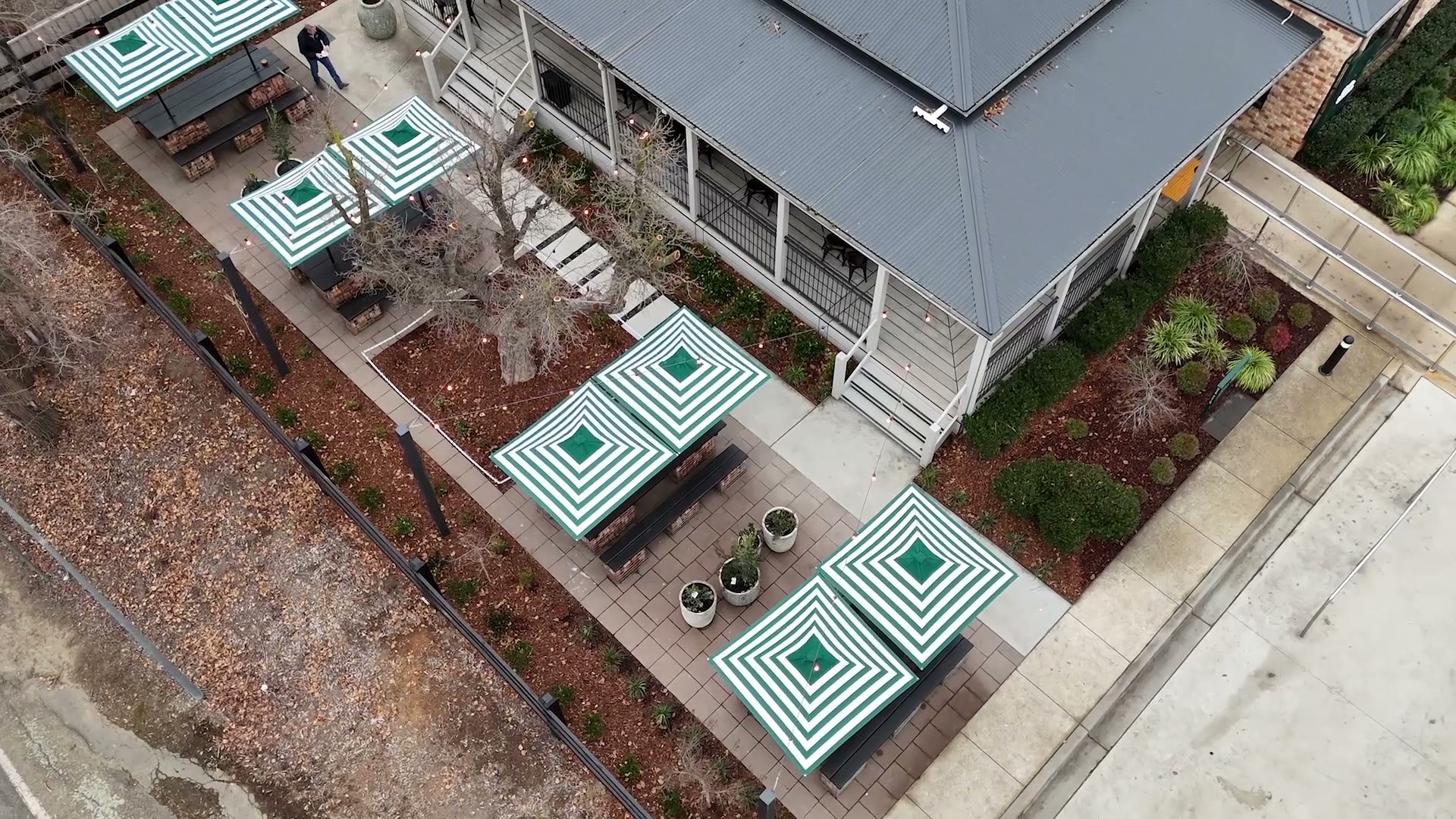 Finished Little Sutton courtyard: green-striped umbrellas, gabion-and-brick seating, string lights and new planting
